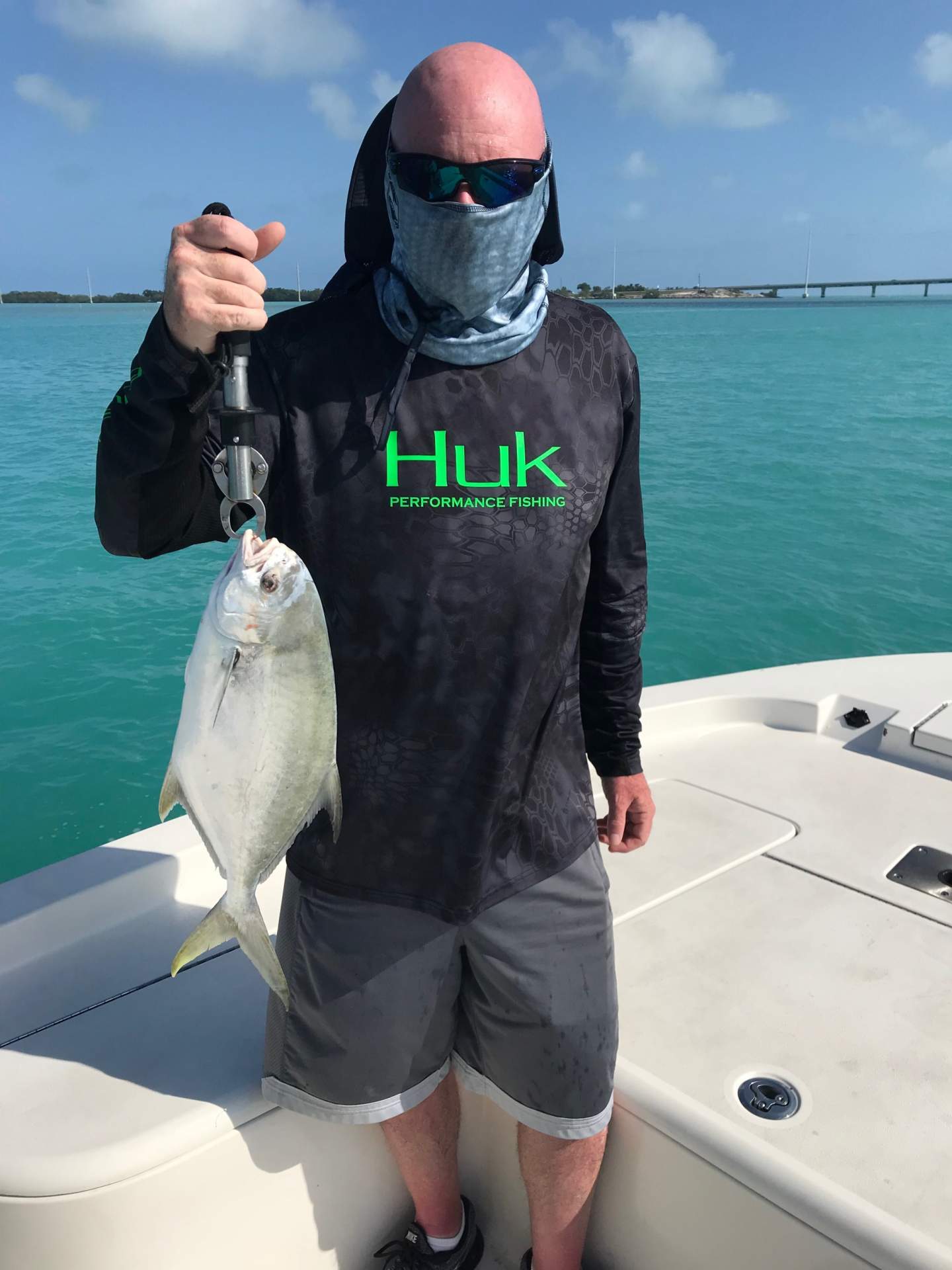 Man wearing black hulk fishing shirt holding pompano fish