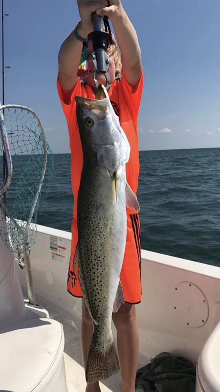 Young boy holding fish up with both hands