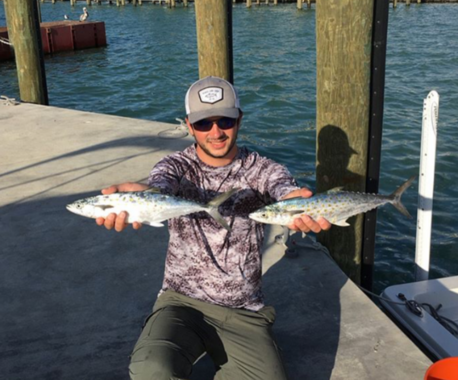 Man smiling holding one spanish mackerel in each hand